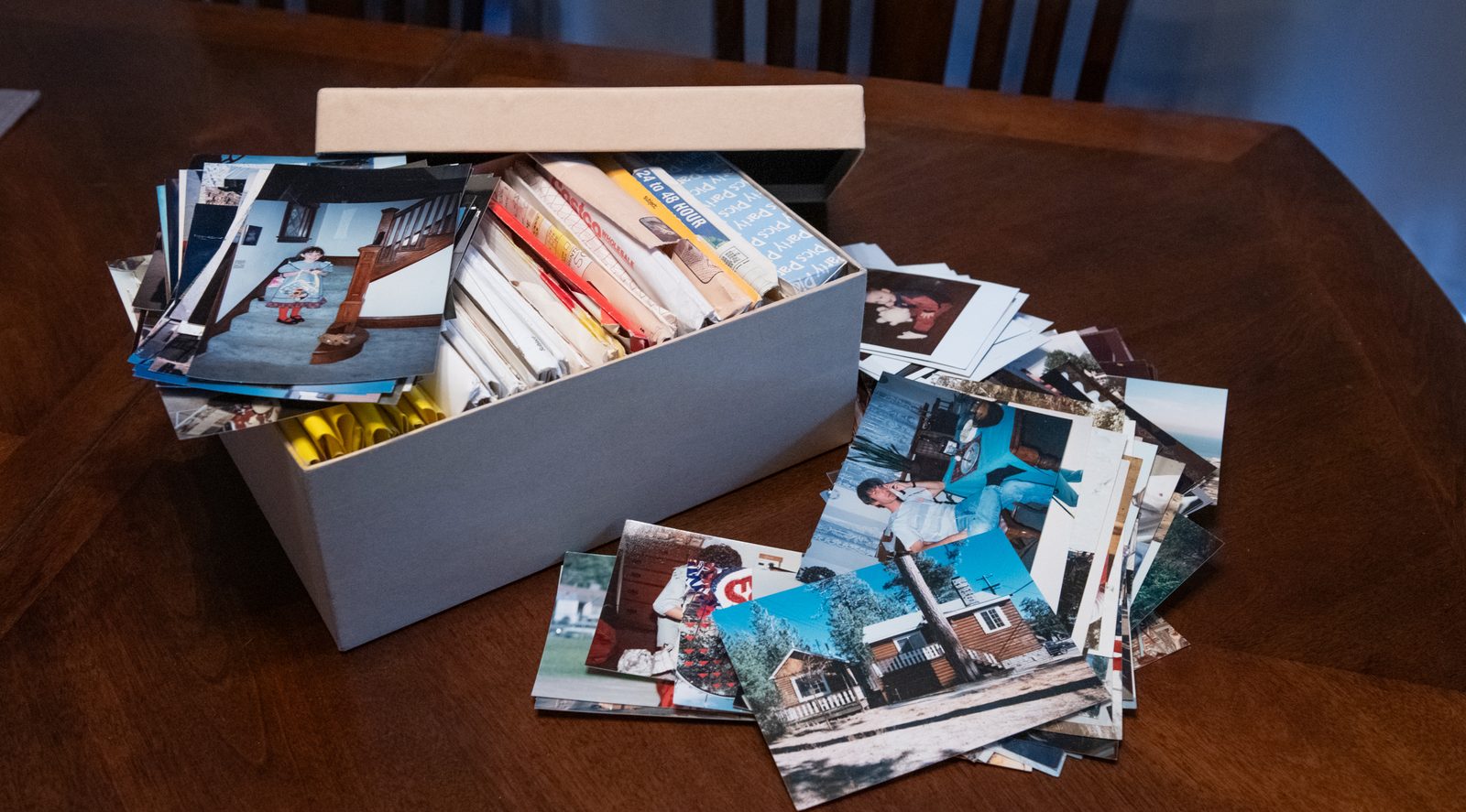A box overflowing with old photo prints, ready for scanning
